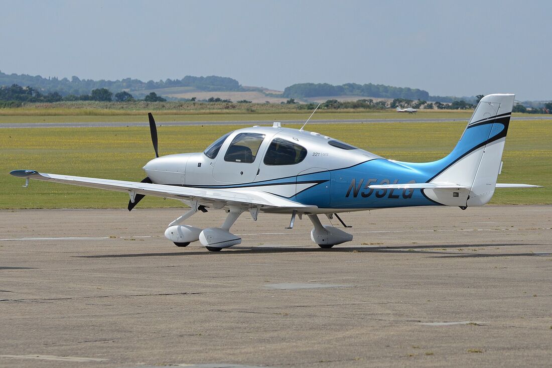 A white Cirrus SR22T with blue trim parked on an apron, seen from the side